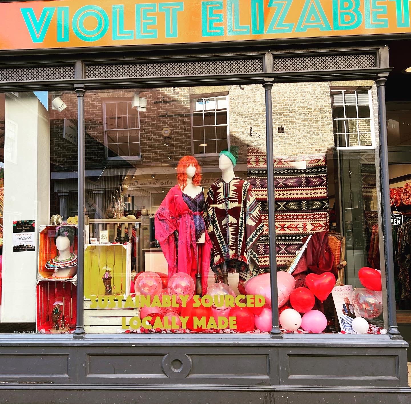 Storefront with mannequins, balloons, and 'Violet Elizabeth' sign.